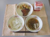 テーブルクロスに並べられたごはん・牛乳・五目汁・ぶりの竜田揚げ・じゃがいものきんぴらの写真