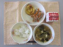 テーブルクロスに並べられたごはん・牛乳・わかめスープ・かに玉・ピリ辛丼の写真