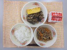 テーブルクロスに並べられたごはん・牛乳・細切りやさいの炒め煮・厚焼きたまご・ひじきと大豆の煮付けの写真