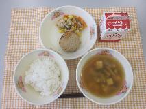 テーブルクロスに並べられたごはん・牛乳・すまし汁・キャベツ入りつくね・きのこの和風ソテー・コーヒー糖の写真