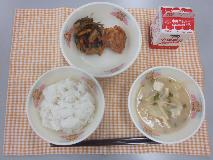 テーブルクロスに並べられたごはん・牛乳・白みそ汁・とり肉の風味揚げ・糸切りこんぶの煮付けの写真