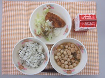 テーブルクロスに並べられたわかめごはん・牛乳・ふ玉汁・あじフライ・ボイルキャベツ・パックソースの写真