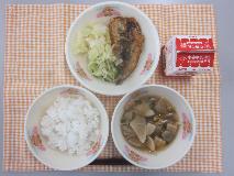 テーブルクロスに並べられたごはん・牛乳・五目汁・いわしのかば焼き丼・しんこあえ〔たくあん漬〕の写真
