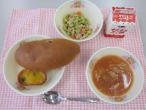 テーブルクロスに並べられたレーズンロールパン・牛乳・ミネストローネ・かぼちゃグラタン・ツナとえだ豆のソテーの写真