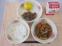 テーブルクロスに並べられたごはん・牛乳・のっぺい汁・大豆と小魚のごまがらめ・みかんの写真