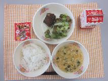 テーブルクロスに並べられたごはん・牛乳・かきたま汁・かつおのおかか煮・きゅうりあえ〔きゅうり漬け〕・黒とう大豆の写真