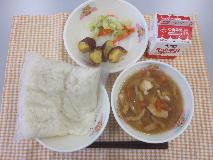 テーブルクロスに並べられた白玉うどん・牛乳・きつねうどん・大学いも・キャベツ炒めの写真