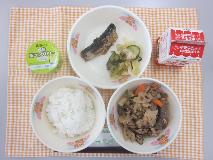 テーブルクロスに並べられたごはん・牛乳・いりどり・いわしのうめ煮・きゅうりの塩こんぶあえ・なしゼリーの写真