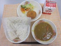 テーブルクロスに並べられたソフトめん・牛乳・米粉のカレーソース・えびカツ・フレンチサラダ・フレンチドレッシングの写真