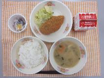 テーブルクロスに並べられたごはん・牛乳・白みそ汁・あじカレーフライ・キャベツソテー・なっとうの写真