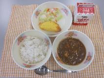 テーブルクロスに並べられた麦ごはん・牛乳・米粉のハヤシライス・オムレツ・コールスローサラダ・コールスロードレッシングの写真