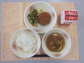 テーブルクロスに並べられたごはん・牛乳・五目汁・キャベツ入りメンチカツ・ひじきと大豆のサラダ・和風ドレッシングの写真