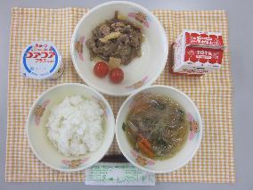 テーブルクロスに並べられたごはん・牛乳・はるさめスープ・ぶた肉のしょうが炒め・ミニトマト・ヨーグルトの写真