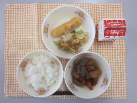 テーブルクロスに並べられたごはん・牛乳・煮みそ・いかの天ぷら・ごまあえの写真
