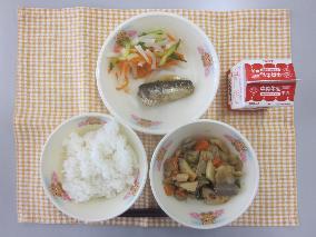 テーブルクロスに並べられたごはん・牛乳・いりどり・いわしのしょうが煮・三色なますの写真