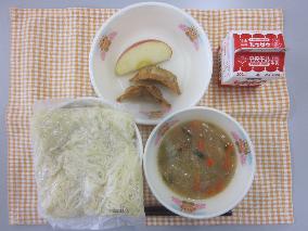 テーブルクロスに並べられた中華めん・牛乳・とんこつしょうゆラーメン・ひじき入りぎょうざ・りんごの写真