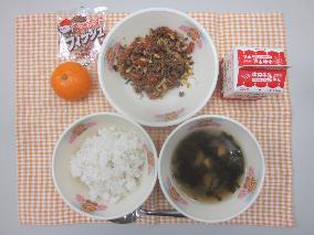 テーブルクロスに並べられた麦ごはん・牛乳・わかめスープ・いなりビビンバ・みかん・アーモンド小魚の写真