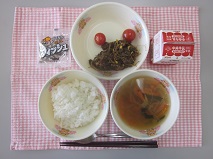 テーブルクロスに並べられたごはん・牛乳・はるさめスープ・ビビンバ・ミニトマト・かんそう小魚の写真
