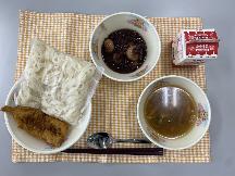 テーブルクロスに並べられたきしめん・牛乳・五目きしめん・にぎすのフライ・ミニぜんざい・パックソースの写真