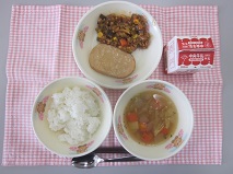テーブルクロスに並べられたごはん・牛乳・やさいスープ・ボロニアソーセージ・おいしくってまよっちゃう豊川スペシャルミートソースの写真