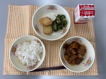 テーブルクロスに並べられたわかめごはん・牛乳・生揚げのみそ煮・うの花はんぺん・きゅうりの塩こんぶあえの写真