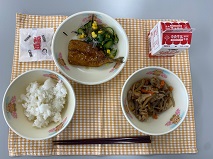 テーブルクロスに並べられたごはん・牛乳・五目きんぴら・いわしのかば焼き丼・海そうサラダ・せつぶん豆・たまねぎドレッシングの写真
