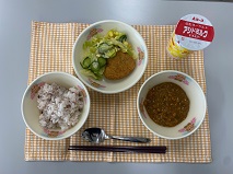 テーブルクロスに並べられた五こくごはん・はっこう乳・キーマカレー・ハートのパンプキンコロッケ・コーンサラダ・コーンドレッシングの写真