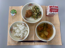 テーブルクロスに並べられたごはん・牛乳・ゆばのすいもの・とりのから揚げ・赤しそあえ・ミニゼリー（洋なし）の写真