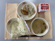 テーブルクロスに並べられた中華めん・牛乳・とんこつしょうゆラーメン・揚げぎょうざ・もやし炒めの写真