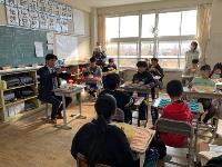 教室で机に給食を並べ椅子に座って食べながら懇談をする児童たちと豊川市長の写真