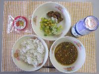 オレンジと白のチェック柄の布の上にお椀によそった麦ごはん、お椀によそったいなりの入ったキーマカレー、お皿に盛った青じそポテトとグリーンアスパラガスのサラダ、牛乳瓶に入った牛乳、いちごあんの水まんじゅうがのった写真