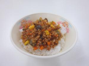 お椀の中に大葉、キャベツ、にんじん、トマト、なす、ピーマン等を使ったミートソースがご飯の上に盛られている写真