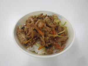 お椀の中にトマト、キャベツ、にんじん、こまつな、みそ等をつかった具材がご飯の上に盛られている写真