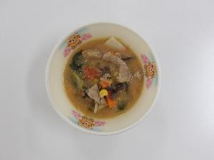 お椀の中ににんじん、たまねぎ、コーン、豚肉、ほうれんそう、きくらげ、トマト、キャベツ等の具材を使ったスープが盛られている写真