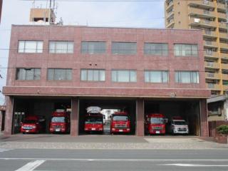 消防車両が5台、救急車両が1台並んだ、赤茶色の壁の豊川市消防署本署庁舎の写真