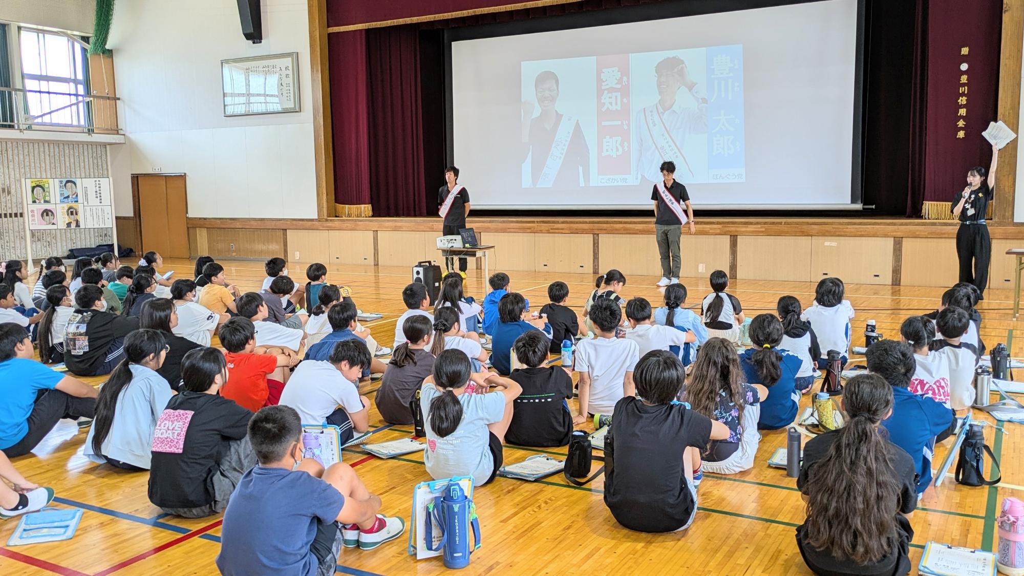 模擬投票の演説を聞く代田小学校の児童の写真です。