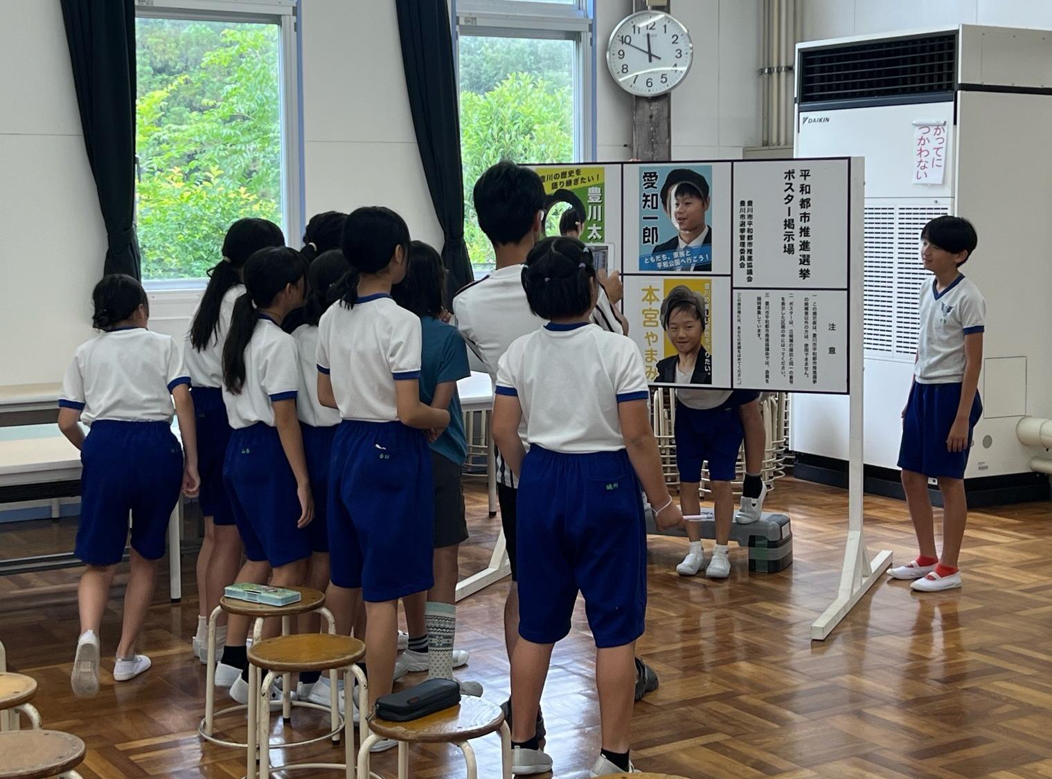 ポスター掲示板顔はめパネルで遊ぶ一宮南部小学校の児童の写真です。