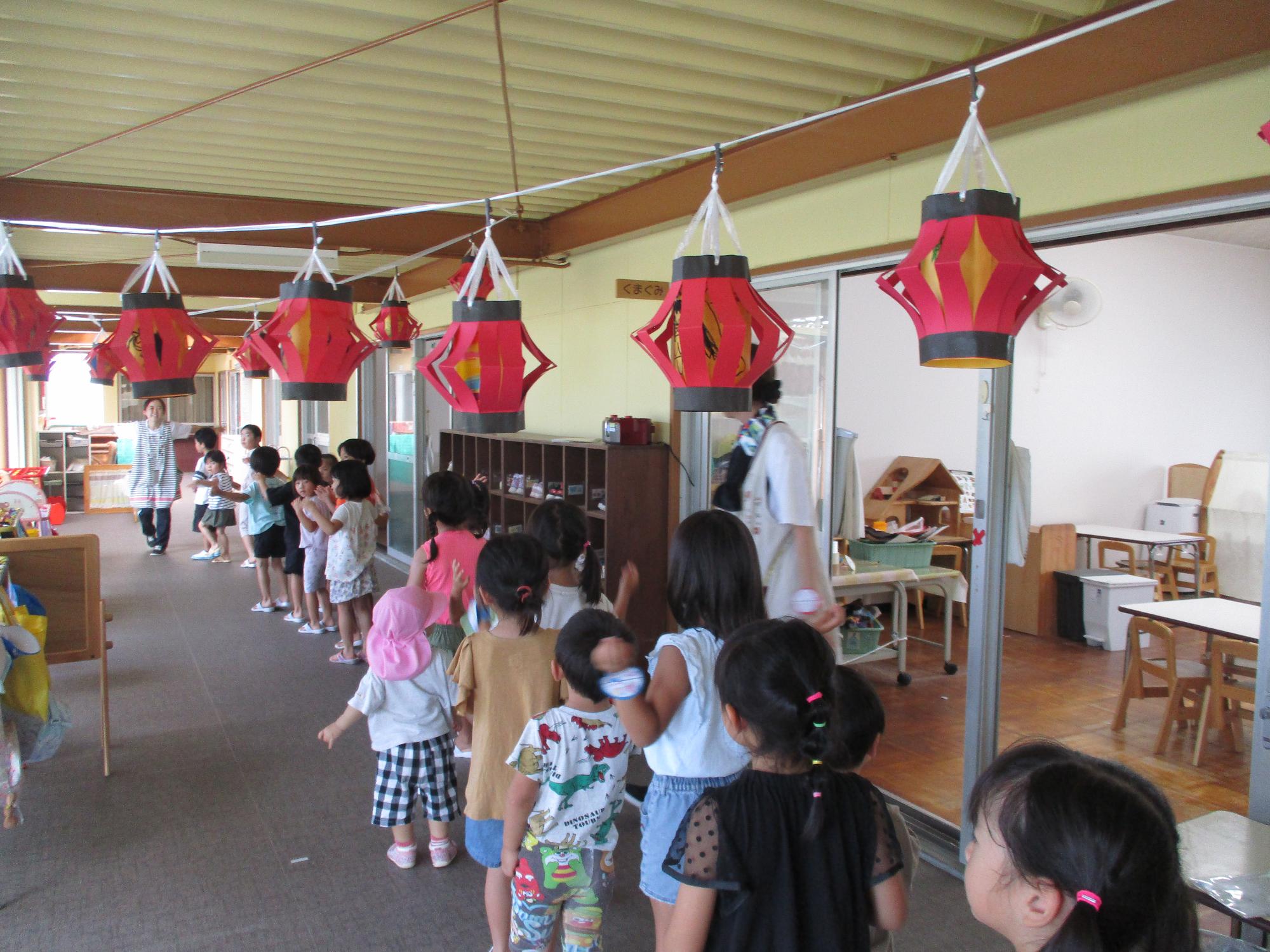 ちょうちんの下で盆踊りを踊っている子どもたち