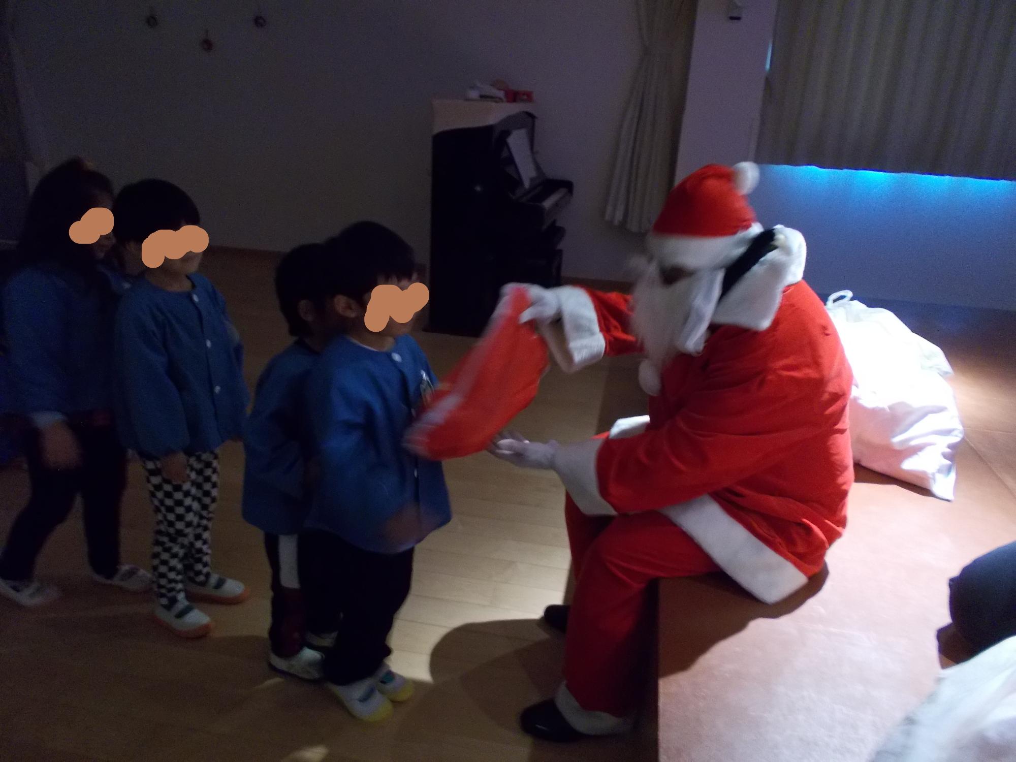 サンタさんにプレゼントを並んでもらう子どもたち