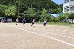 白線が引かれた校庭を走る、4人の児童達の写真