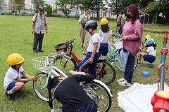 芝生の広場で自転車の整備をしている児童たちの写真